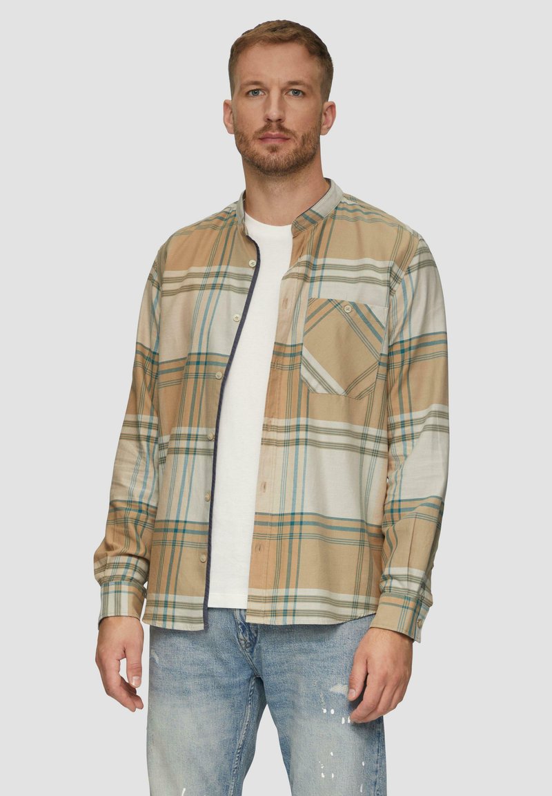 Geruite shirt in beige, groen en blauw met een knoopsluiting, lange mouwen, een borstzak en een off-white onderhemd. Spijkerbroek.