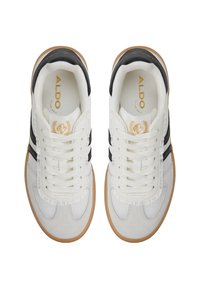 Scarpe sportive bianche e nere con una tomaia in suede e tessuto, caratterizzate da lacci piatti, una suola in gomma e dettagli di branding dorati.