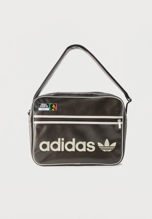 Bolso de hombro negro de Adidas con cremallera blanca, logo y parche con el texto "El fútbol es libertad" en el bolsillo delantero.
