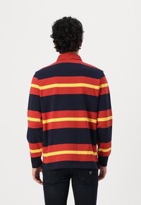 Langærmet polo-shirt med brede horisontale striber i rød, gul og marineblå. Lavet af tekstureret bomuldsstof med krave.