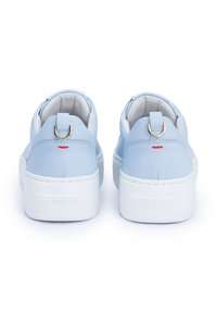 Hellblaue Leder-Sneaker mit einer weißen Sohle, die ein goldfarbenes Ringakzent und eine rote Stichdetail an der Ferse aufweisen. Insgesamt glatte Textur.