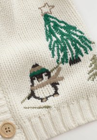 Weißer Strickstoff mit einem Pinguin, der einen braunen und grünen Hut trägt, sowie einem grünen Baum mit einem Stern, verziert mit braunen Akzenten und Textur.