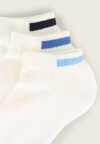 Conjunto de tres calcetines blancos con textura acanalada, cada uno con una franja de color—negra, azul oscuro y azul claro—en el puño.
