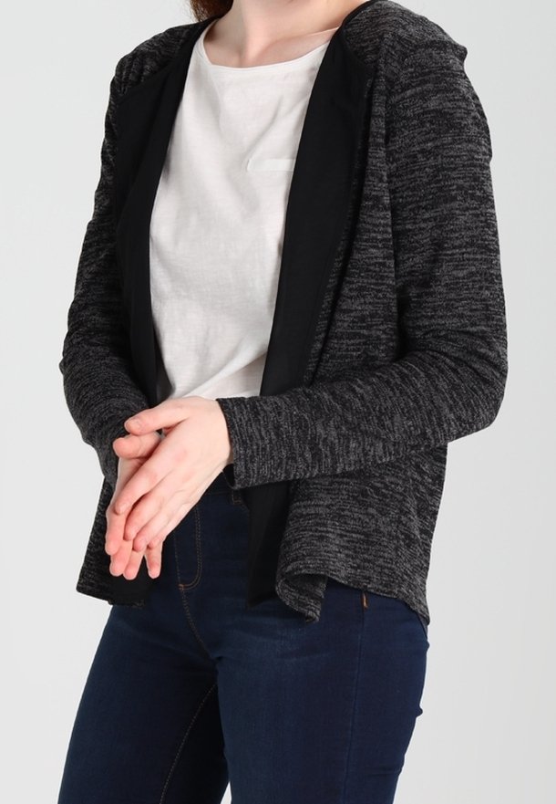 Svart och grå blandad stickad kofta med en huva, öppen frontdesign, texturerad tyg och långa ärmar. Matchas med en ljusfärgad topp.