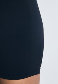 Sorte kompresjonsshorts med glatt tekstur, tettsittende design og lengde til midten av låret, med en sømløs midje.