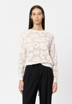 Light beige sweater with textured floral pattern, rounded neckline, and long sleeves. Paired with black high-waisted trousers.