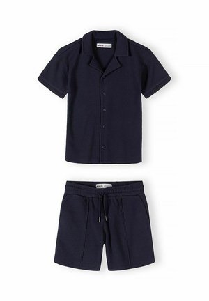 Granatowa koszula na krótki rękaw z guzikami i kołnierzykiem oraz dopasowane szorty ze ściągaczem, oba wykonane z fakturowanej tkaniny.