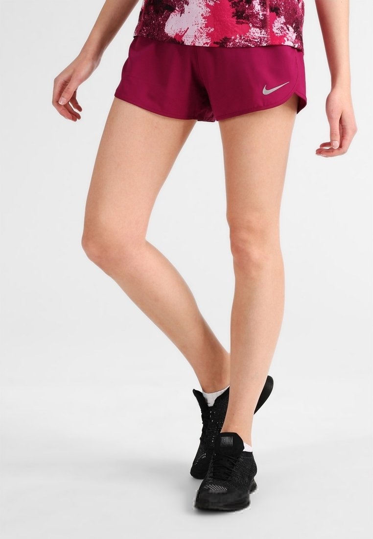 Pantalones cortos deportivos morados con el logo de Nike, que presentan un diseño ligero y una textura suave, combinados con zapatos deportivos negros.