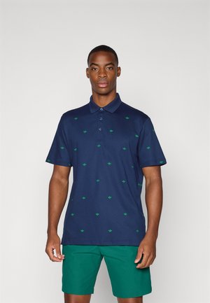Marinblå polo-shirt med gröna bladmönster, tre-knapps knäppning och korta ärmar. Bärs med gröna shorts. Slätt, lätt tyg.