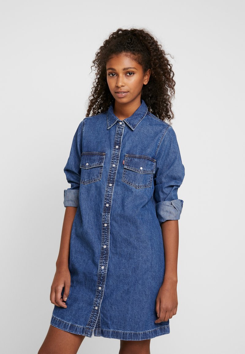 Heledad denimsärk sinises. Omab nööbist sulgemist, kahte rinnataskut ja rullitud varrukaid. Pehme tekstuur koos veidi vabalt istuva lõike ja räbalate äärtega.