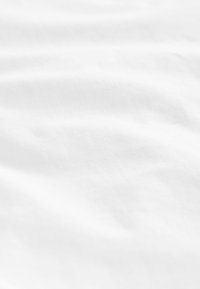 Tissu en coton blanc avec une texture douce et lisse, présentant de légères rides et plis, créant un aspect ondulé.