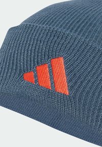 Gorro de punto en azul oscuro con textura acanalada. Presenta un prominente logotipo bordado en rojo con tres rayas diagonales.