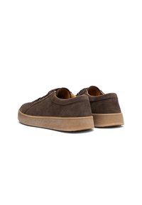 Zapatillas de gamuza marrón con perfil bajo, puntera redonda y suela de goma marrón contrastante. Presenta un diseño de cordones y una superficie texturizada.