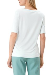 Lichtblauw T-shirt met korte mouwen van zachte stof, met een ronde halslijn en een relaxed fit, gecombineerd met lichtgroene op maat gemaakte broek.
