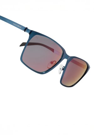 Kvadrātveida saulesbrilles ar zilu metāla rāmi un rozā krāsas pakāpeniska toņu pāreja lēcām. Raksturīgās iezīmes ietver deguna spilventiņu un zīmola logotipu uz kājiņām.