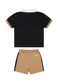 Polo noir avec un col blanc et des accents beige, assorti à un short beige avec des bandes latérales noires et le logo "BOSS" au dos.