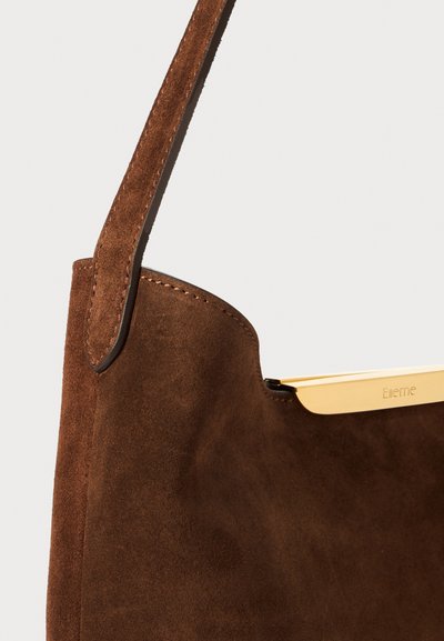 Sac en daim marron avec un accent en métal doré, présentant une forme structurée et une seule bandoulière pour le porter.