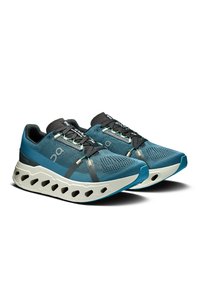 Baskets de course avec une tige en mesh teal, des accents noirs et une semelle distincte blanc cassé avec des motifs découpés pour la ventilation.