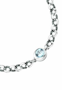 Bracciale in argento con maglie ovali e un evidente accento di una gemma tonda di un blu chiaro. Finitura metallica liscia, texture lucida.