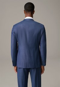 Giacca di abito navy con un motivo testurizzato, dotata di una singola apertura, rever a punta e due bottoni. Design slim-fit con dettagli sartoriali.