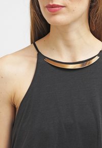Top senza maniche nero con una texture liscia, caratterizzato da un accento metallico dorato lungo il collo. Design leggero e casual.