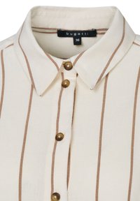 Cremfarbene Hemdbluse mit braunen vertikalen Streifen, klassischem Kragen und braunen Knöpfen. Der Stoff wirkt leicht und strukturiert.