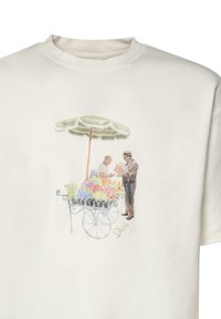 Dos hombres en un carro de flores bajo una sombrilla a rayas, uno sosteniendo un ramo, impreso en una camiseta blanca.
