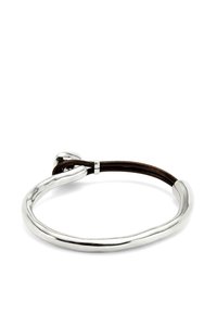 Pulsera de metal plata con un diseño suave y curvado, que presenta una correa de cuero marrón sujeta por un pequeño acento metálico.