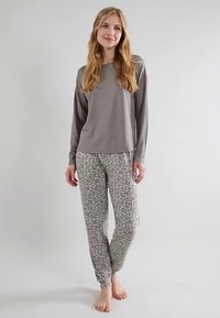 Pelēks garroku tops kopā ar pelēkām pidžamas biksēm ar leoparda rakstu. Mīksts audums, brīvs piegriezums un elastīgi aproces bikšu galos. Kurpes nav redzamas.