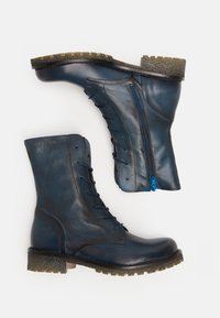 Blaue Leder-Stiefeletten mit einer strukturierten Gummisohle, seitlichem Reißverschluss und kontrastierenden blauen Schnürsenkeln an der Vorderseite.