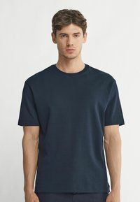 Mörkblå bomullströja med korta ärmar, rundad hals och en enkel design. Mjuk textur och rak skärning. Inga synliga mönster eller detaljer.