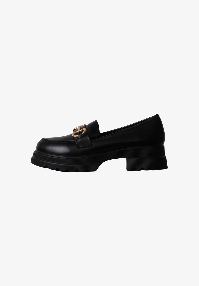 Mocassin en cuir noir avec semelle épaisse et boucle décorative dorée sur le dessus, vue de côté sur fond blanc.