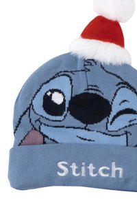 Berretto di maglia azzurro chiaro con un grafico del volto di un personaggio. Accento con cappello di Babbo Natale rosso con pom-pom bianco. "Stitch" ricamato alla base.