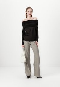 Black off-the-shoulder top with gathered texture, paired with light grey wide-leg trousers. Accessories include a white handbag and black heels.