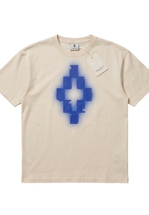 Maglietta beige a maniche corte con una forma a diamante geometrica blu pixelata stampata al centro e un piccolo tag bianco attaccato vicino al colletto.