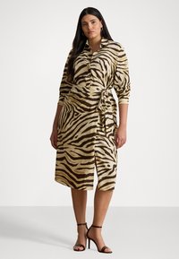 Kjole med zebra mønster som har en beige og brun fargeskjema, kragehals, lange ermer og en knyttet midje.