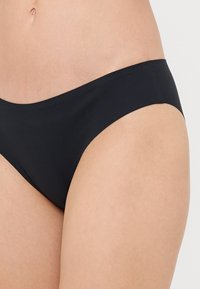 Schwarzer Bikini-Unterteil mit glatter Textur, niedrigem Schnitt, minimaler Abdeckung und sauberen Kanten. Keine sichtbaren Muster oder Beschläge.