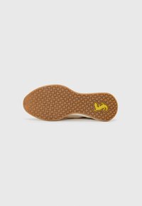 Schuhsohle mit einer strukturierten braunen Gummoberfläche, die ein gelbes Logo aufweist und eine glatte, abgerundete Form hat, die für Traktion und Komfort geeignet ist.