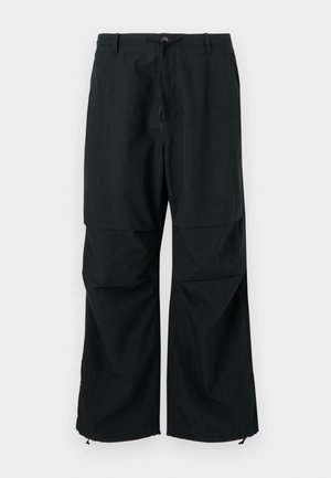 Black, wide-legged trousers featuring a drawstring waist and elastic hems. Made of lightweight, textured fabric. Simple design.