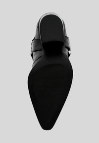 Scarpa nera con tacco caratterizzata da una suola in gomma texturizzata. La parte superiore è realizzata in pelle liscia con una cintura alla caviglia e dettagli in metallo argentato.