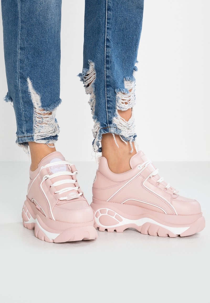 Rosa chunky sneakers med en slät läderutsida, vita accenter och mönstrad sula, kombinerade med slitna blå denim.