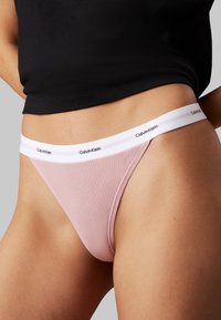 Roze geribbelde slip met een witte elastische tailleband met "Calvin Klein" branding. Zachte textuur met een aansluitend ontwerp.