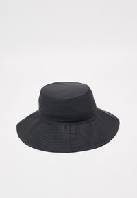 Černý bucket klobouk z hladké látky; má širokou, pružnou krempu a zaoblenou korunu s viditelnými švy.