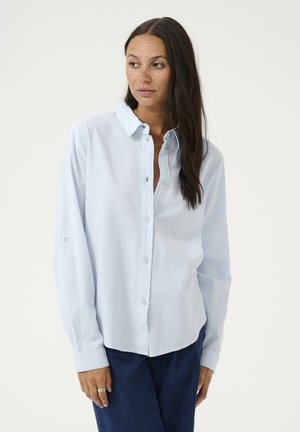 Camisa abotonada de color azul claro, hecha de tela texturizada, con mangas largas, cuello y botones en la parte delantera. Corte casual con puños enrollados.