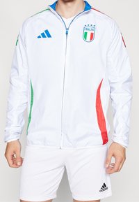 Vit zip-up jacka med blå accenter och röda och gröna sidostreck, med Italiens landslagsfotbollens logo på bröstet.