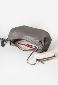 Grauer Leder-Clutch, die geöffnet ist und das beigen gemusterte Innenfutter sowie ein Reißverschlussfach zeigt, mit einem passenden kleinen beigen Reißverschlussbeutel daneben.