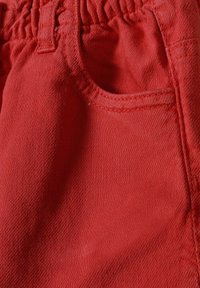 Röda bomullsshorts med elastisk midja och en sidoficka med en strukturerad yta. Sömmarna är fint sydda för hållbarhet.