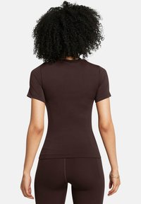 Krótki rękaw, dopasowany top z ciemnobrązowego materiału, charakteryzujący się gładką fakturą i przeszyciami na plecach.