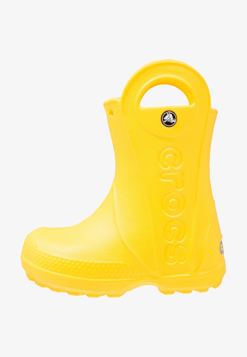 Botte en caoutchouc jaune avec un bout arrondi, semelle texturée et poignée circulaire. Présente le logo "crocs" sur le côté. Matériau lisse et imperméable.