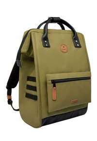 Olive green backpack with black leather accents, top handles, front zipper pocket, and side webbing detail. Textured bottom panel for durability.